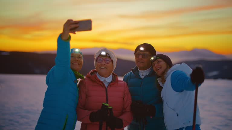 SLO MO A senior couple and their two mid-adult daughters are taking selfies with a mobile phone in a snowy setting