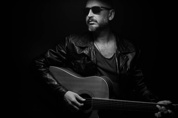 istock Guitarist on stage. Man playing guitar in a dark environment 1610281180