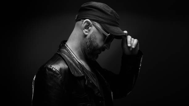 Stylish handsome man wearing leather jacket with sunglasses looking down
