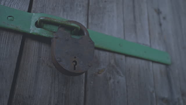 Vintage grey iron padlock hanging on old wooden door