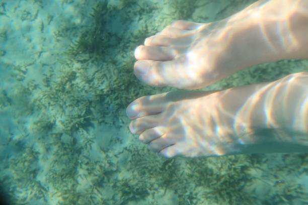 エジプトのシナイ半島のラス・シタンの青いターコイズブルーの水の下の女性の足 - red sea taba sand reef ストックフォトと画像