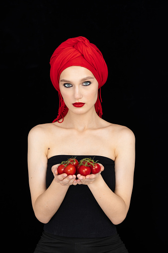 portrait of attractive caucasian smiling woman isolated on black studio shot with tomatos