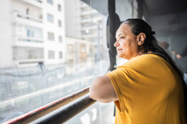 istock Contemplative senior woman looking through the window 1610372319