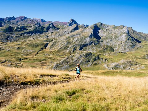 Hiking woman going around the Midi D'Ossau Peak, French Pyrenees