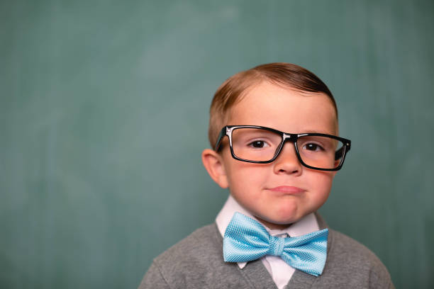 Portrait of a retro nerd in front of a blackboard in a classroom.