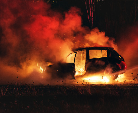 Firefighters extinguish a car fire on Nova Scotia's highway 102.  Shot at high iso with light grain.