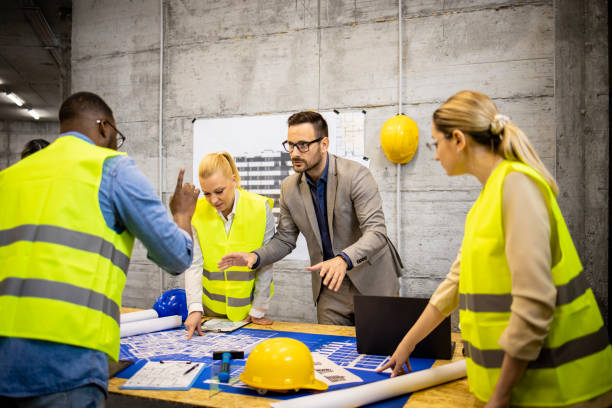 istock Contractor and architects analyzing building plan and blueprint together at construction site. 1610496296