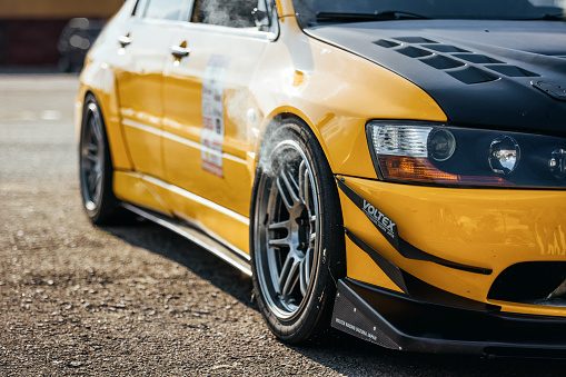 yellow Milsubishi Lancer evolution at local track driving event with smoke coming out of the front wheel arches