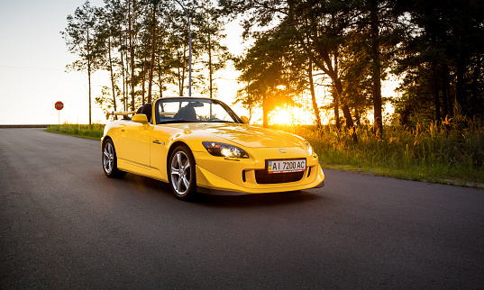 Kyiv region, Ukraine - July 17 2014: . Static shot of japanese roadster yellow Honda S2000 Type S parked on forest road on sunset.
