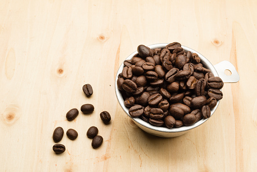 Roasted coffee beans in a 1/2 cup measure to prepare a correct amount of expresso coffee.