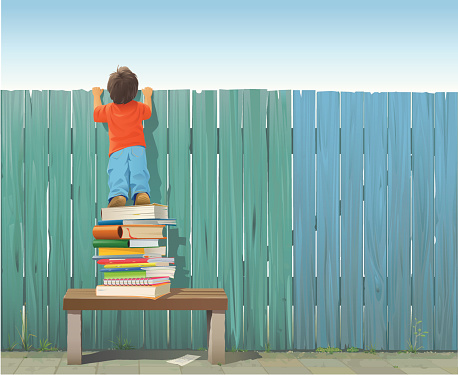 Schoolboy on pile of books looking over fence