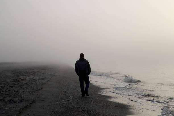 lonely man walking on ビーチ - 寂しさ ストックフォトと画像