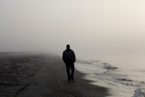 Man walking alone on a foggy beach