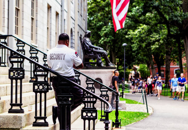 Cambridge, MA, USA - Jun 29, 2022: Visitors to the Harvard Yard, the oldest part of the Harvard University campus in Cambridge, Massachusetts, wait in line to take photos with the John Harvard Statue.