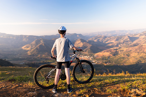Man standing with his mountain bike, contemplating the mountain landscape in the background