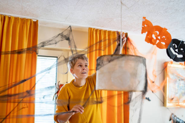 istock A woman hanging halloween decorations for a party 1610666986