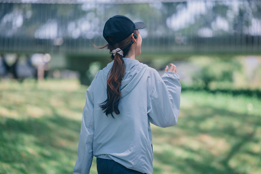 Fashionable female runners dressed in modern gear, finds peace in rhythmic beats. Recharge energy in the midst of life's steady, serene flow. Embrace tranquility while jogging through public parkway.