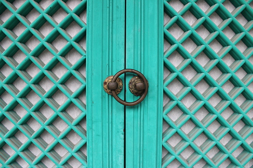 Closeup of turquoise blue shutter door and lock, on temple entrance