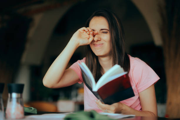 istock Tired Woman reading a Book Rubbing her Eyes 1610833519