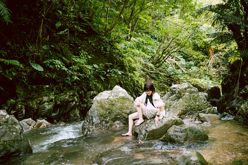 A woman relaxing while enjoying nature in the mountains where the river flows