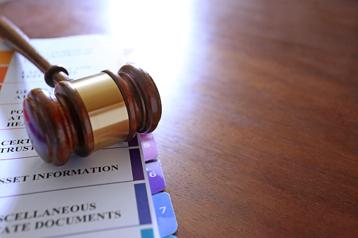 A gavel rests on top of an open notebook of living trust documents.