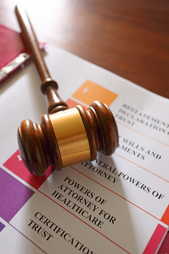 A gavel rests on top of an open notebook of living trust documents.