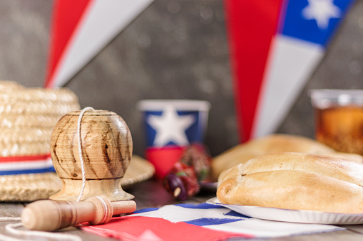 Fiestas Patrias Chile September 18, Independence Day. Close up Empanadas, Anticuchos, mote con huesillo, chicha or wine, Sombrero huaso chupallas de paja y emboque, on wooden table with flag. Chilenidad