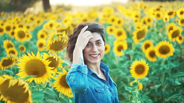 Beautiful young woman in a field with blooming sunflowers