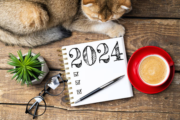 istock New year resolutions 2024 on desk. 2024 resolutions list with notebook, coffee cup, cute cat on table. Goals, resolutions, plan, cozy, hygge concept. New Year 2024 template 1611171243