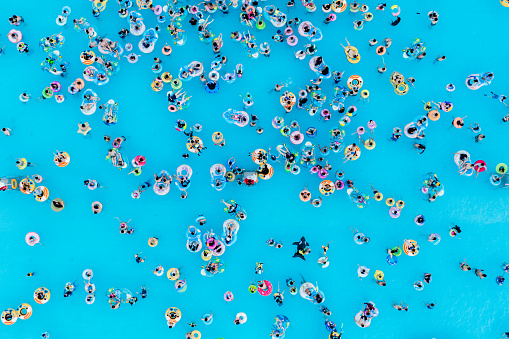This is an aerial view of outdoor swimming pool. It's summer and there are so many people in the swimming pool.