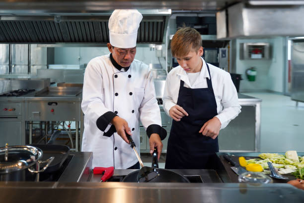 istock Chef teacher teaches cooking to the group children in class kitchen room.  Chef preparing student for learning marking and cooking food at workshop.  Education Concept 1611219208