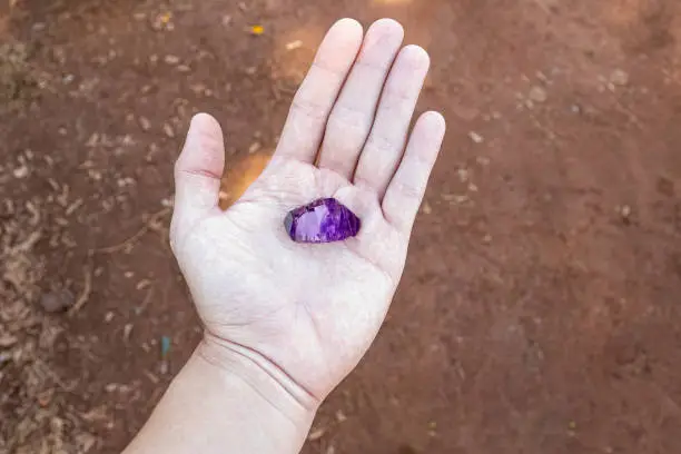 closeup of clean white hand holding piece of amethyst