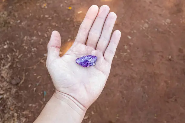 closeup of clean white hand holding piece of amethyst