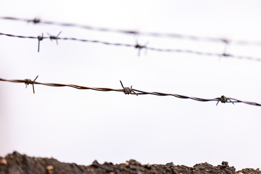 barbed wire on top of a fence with selective focus