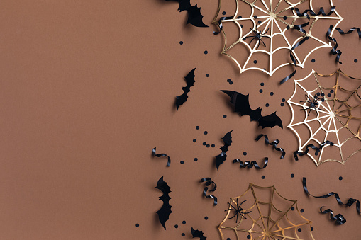 Halloween party decorations from bats, spider web and confetti top view. Happy halloween minimal holiday greeting card flat lay.