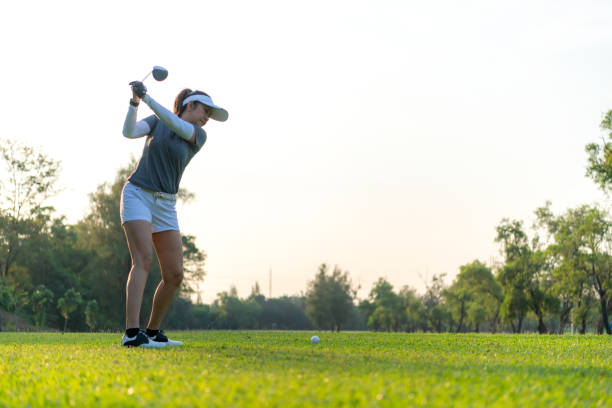 golfeuse femme parcours de balle de golf fairway. les gens style de vie femme jouant au golf s’approchent du tee de sur le fond de coucher de soleil d’herbe verte. - golf golf swing sunset golf course photos et images de collection