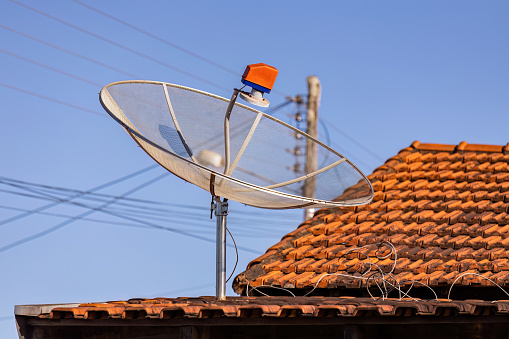 close up of television satellite dish on the roof of a house