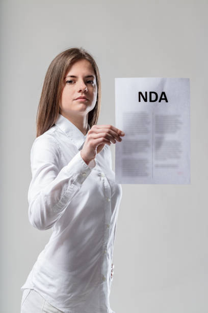 istock Stern woman, white, holds NDA, speech warning 1611385704