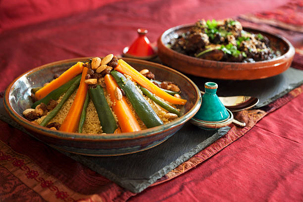 Vegetable couscous and Meat Tagine Vegetable couscous and Meat and prune tagine garnished with fresh coriander and sesame seeds.  Authentic pepper and salt pots and table linen. moroccan culture photos stock pictures, royalty-free photos & images
