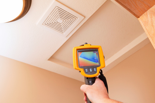An infrared thermal imaging system being used during a home energy audit. The camera is pointed to an attic access hole showing a distinct blue (cold) area within the home’s insulation. The center target area reads 50.7 degrees with a range of 45 to 72 degrees in the area.  Energy audits are performed to determine how efficient the house is and to suggest steps to increase energy efficiency.