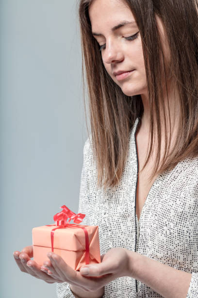 istock Woman gently holds small gift; calm look 1611414213