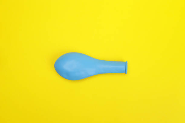 istock Unblown blue shaped balloon on yellow background 1611455361
