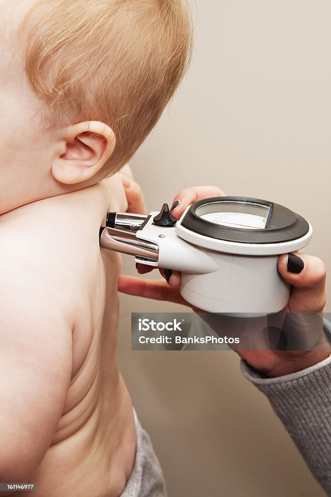 Chiropratico utilizzando un misuratore per misurare la temperatura lungo la colonna vertebrale per neonati - Foto stock royalty-free di Bebé