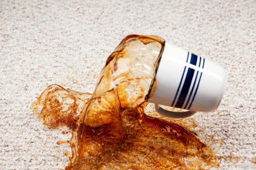 A coffee cup has fallen and coffee is splashing from the cup onto a clean carpet floor. Focus is on the carpet below the cup, at 100% the cup is slightly soft.