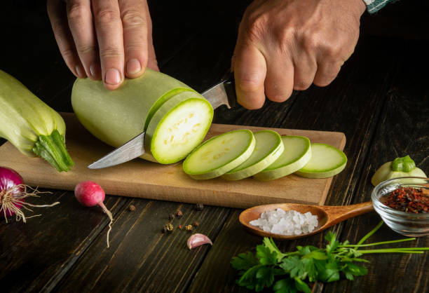 istock The chef cuts zucchini with a knife before roasting with vegetables and spices. Working environment on the kitchen table 1611518146