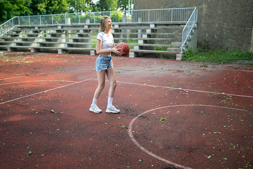 Woman with ball in a street basketball