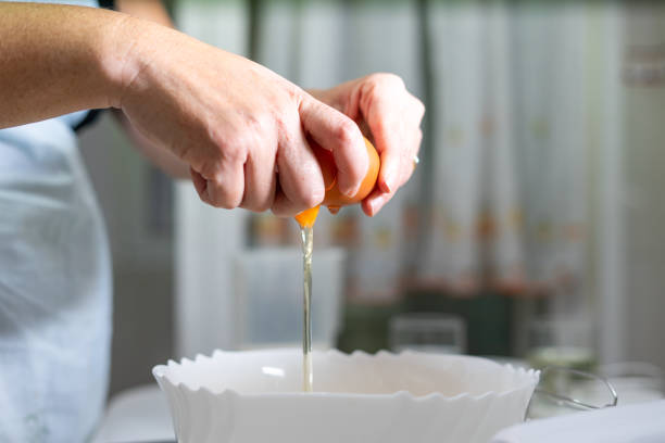 istock Close up of female hands breaking an egg that into a white bowl. 1611530598