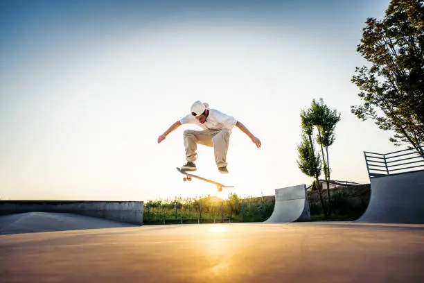 Skater man doing kickflip on the ramp at skate park - Stylish skaterboy training outside - Extreme sport life style concept