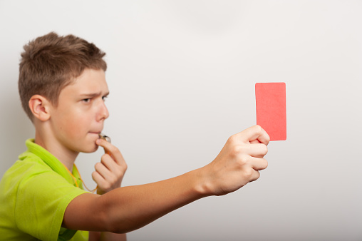 a teenage boy with whistle and red card looks like a sports coach or referee
