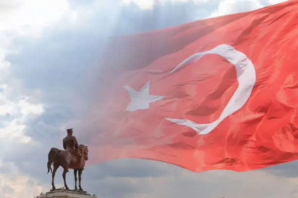 Waving Turkish Flag and Ataturk monument. National holidays of Turkiye concept photo.